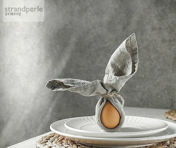 Food  Food  Festive Easter table setting. Funny Easter bunny made of egg and linen napkin on plate. Gray background