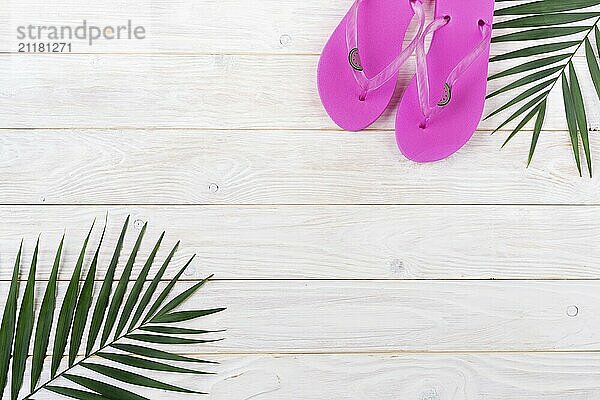 Vacation travel planning simple background of palm leaves and flip flops on white planks flat lay with copy-space