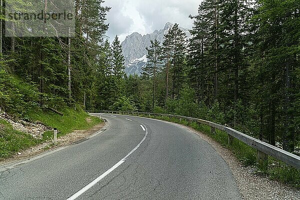 Wide angle photo of beautiful road for cars in the woods with mountains in the back