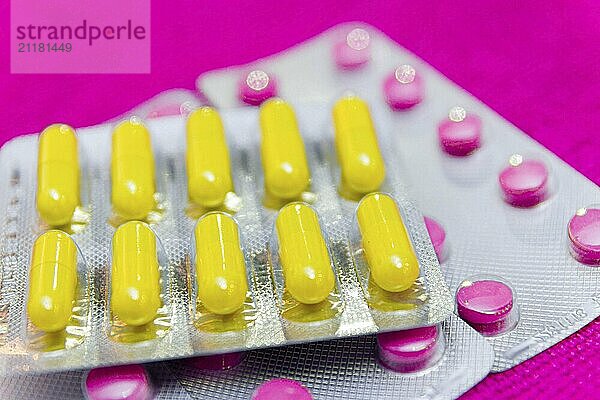 Colorful flu pills in blisters on a pink background