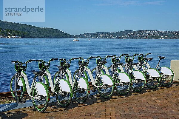 Group of green bicycles on the lakeshore overlooking a tranquil mountain landscape and blue water  Bergen  Vestland  Norway  Europe