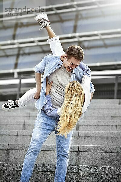 Man giving his pretty girlfriend a piggy back at street smiling at each other on a sunny day