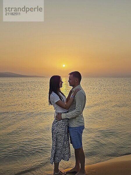 Junges Paar umarmt zusammen auf ein Datum am Meer bei Sonnenaufgang. Frau und Mann auf einer Hochzeitsreise trifft die unten am Strand. Sommerurlaub  Liebe und Romantik Konzept