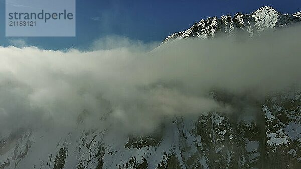 Fliegen durch schöne weiße flauschige Wolken zwischen hohen felsigen Bergen. Dolomiten Alpen Berge  Italien  Europa