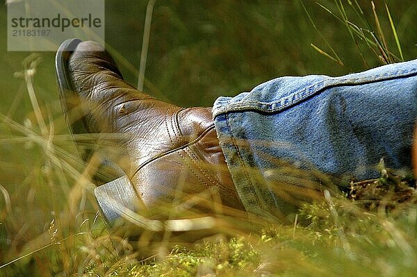 Der Stiefel eines Mannes  der sich auf einer Wiese an einem sonnigen Tag entspannt