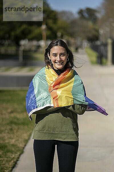 Lesbisches Mädchen eingewickelt in LGBT Flagge mit glücklichem Ausdruck