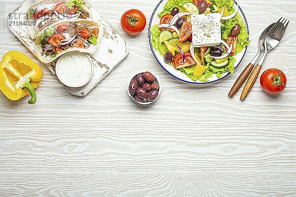 Traditionelles griechisches Essen: Griechischer Salat  Gyros mit Fleisch und Gemüse  Tzatziki Sauce  Oliven auf weißem rustikalen Holztisch Hintergrund von oben. Griechische Küche. Textfreiraum  Lebensmittel Fotografie  food photography  food photography