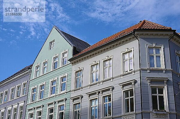 Several old buildings with different facade colours and red roof tiles in front of a blue sky with clouds  Bergen  Vestland  Norway  Europe