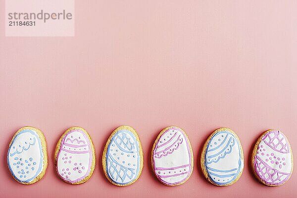 Easter frosted cookies in shape of egg on pink background. Flat lay with copy space