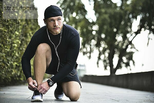 Hands of sportsman with pedometer tying shoelaces on sporty sneaker