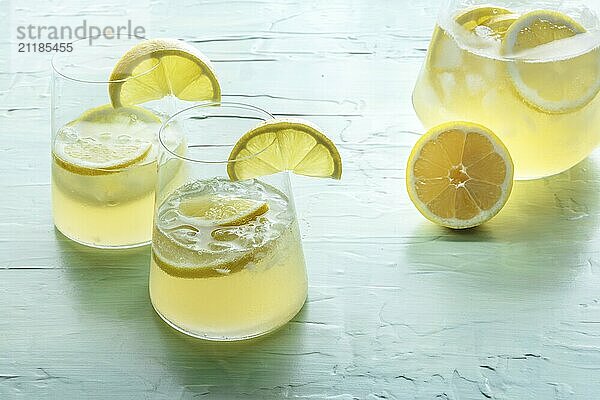 Limonade. Zitronenwasser Getränk mit Eis. Zwei Gläser und ein Krug auf blauem Hintergrund. Detox Getränk. Frischer hausgemachter Cocktail  Lebensmittel Fotografie