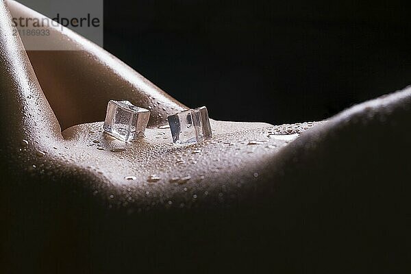 Ice cubes and water drops on woman s body cropped isolated view on black background