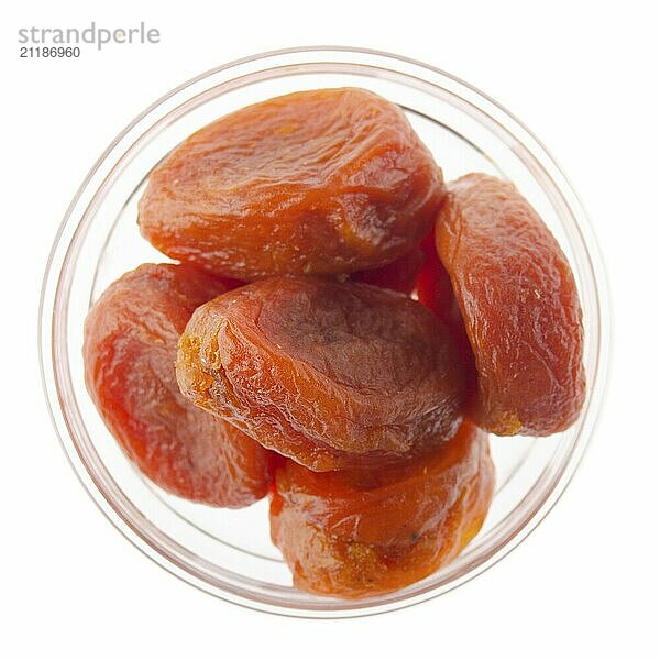 Dried apricots in glass bowl isolated on white background flat lay closeup view