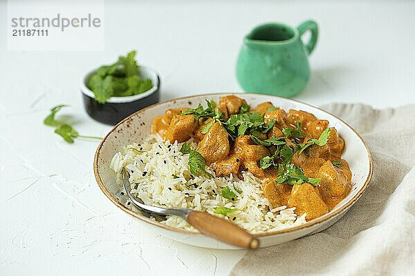 Traditionelles indisches Gericht Hühnercurry mit Basmatireis und frischem Koriander auf rustikalem weißem Teller auf weißem Betonküchentisch  Nahaufnahme mit selektivem Fokus. Indisches Abendessen  Food Fotografie  food photography  food photography