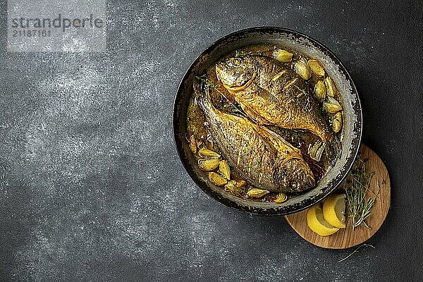 Food  Food  Baked sea bream or dorada with onion and herbs in pan on dark background