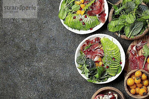 Food  Food  Low carbs bowl. Fresh salad with green spinach  rucola  avocado an ham serrano in white bowl  gray background  top view