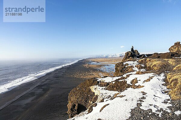 Young woman on the viewing platform on top of Mount Dyrholaey at winter sunset in Iceland