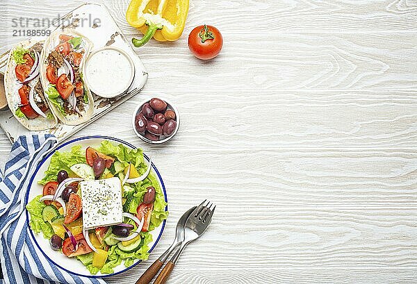 Traditionelles griechisches Essen: Griechischer Salat  Gyros mit Fleisch und Gemüse  Tzatziki Sauce  Oliven auf weißem rustikalen Holztisch Hintergrund von oben. Griechische Küche. Textfreiraum  Lebensmittel Fotografie