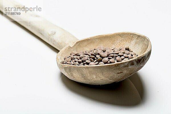 Mountain lentils with wooden spoon on a white background