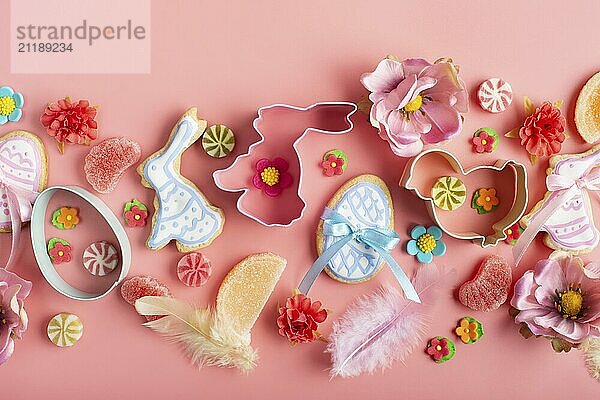 Easter frosted cookies in shape of egg chicken and rabbit  sugar sprinkles  candies  cookie cutters on pink background. Flat lay mockup