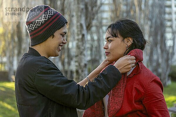 Young woman wrapping a scarf around her girlfriend's neck with care