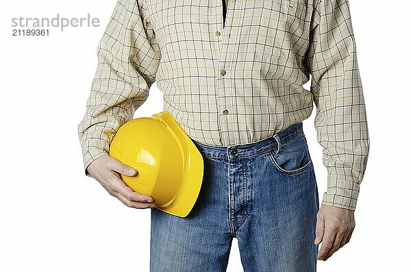 Middle aged caucasian contractor weared in blue jeans and shirt holds yellow hard hat in his hands on white background