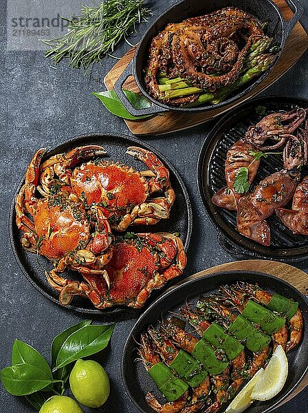 Food  Food  Set of Seafood Dishes. Crabs  octopus  squids and tiger shrimps on cast iron pans and plates on a black background. Top view