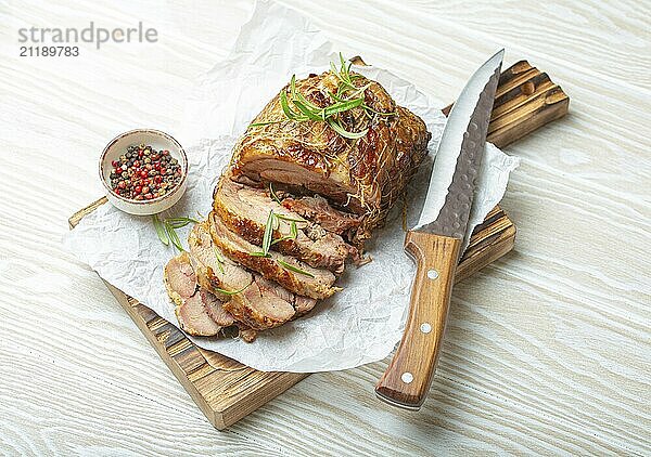 Rolled Truthahn gebraten mit Gewürzen und Kräutern auf Backpapier mit Messer und Holz weißen Hintergrund Draufsicht. Gebackene Schnitt für Scheiben Putenfilet Rolle zum Abendessen  Lebensmittel Fotografie