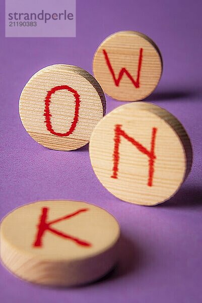 Know word written in red ink on round wood pieces  on a purple background. Knowledge concept. Know now