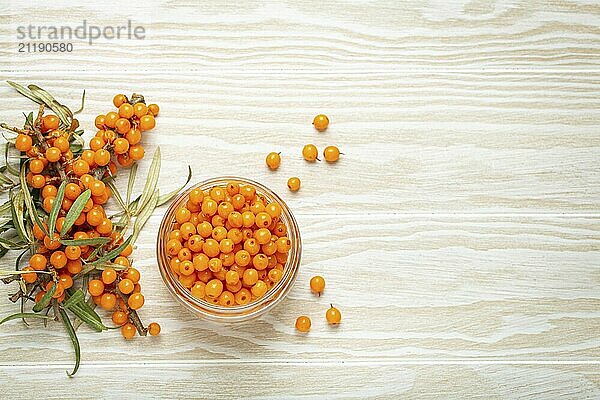 Sanddorn reife Beeren im Glas und Zweige mit Blättern von oben auf weißem hölzernen rustikalen Hintergrund  gut für Haut  Herz  Gefäße und Immunsystem  Food Fotografie  food photography