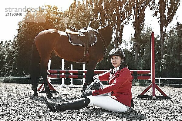 Young jockey Girl and her horse posing after training. She loves the animals and joyfully spends her time in their environment