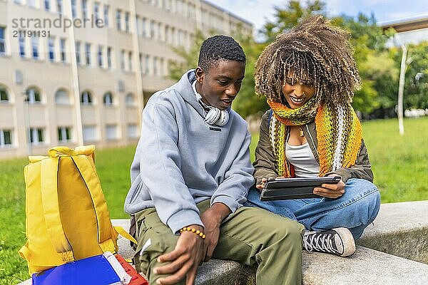 Multiracial friends sharing digital tablet outside university campus