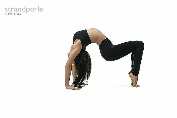 Slim pretty brunette in black sportswear doing handstand isolated view on white background