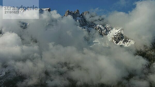 Fliegen durch schöne weiße flauschige Wolken zwischen hohen felsigen Bergen. Dolomiten Alpen Berge  Italien  Europa