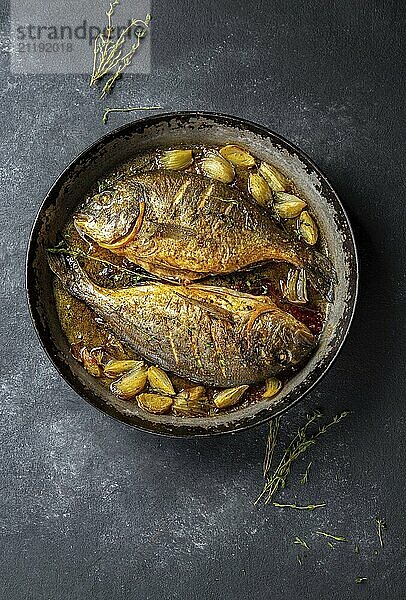 Food  Food  Baked sea bream or dorada with onion and herbs in pan on dark background