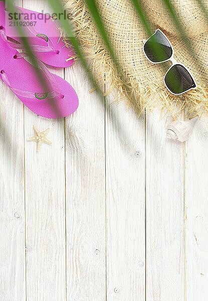 Vacation travel planning simple background of straw hat  sunglasses  palm leaves  flip flops and shells on white planks flat lay with copy-space