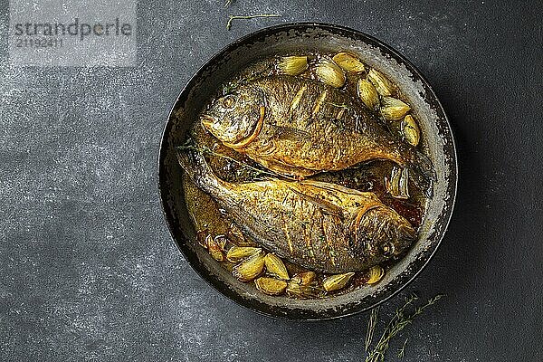 Food  Food  Baked sea bream or dorada with onion and herbs in pan on dark background