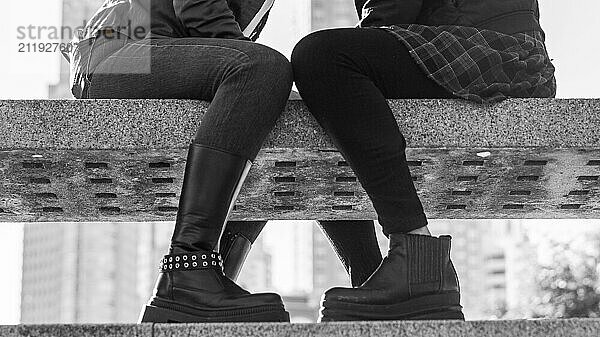 Artistic black and white close-up of a couple of women's legs resting on a bench