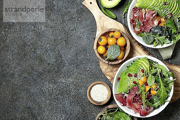 Food  Food  Low carbs bowl. Fresh salad with green spinach  rucola  avocado an ham serrano in white bowl  gray background  top view