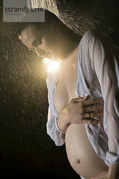 Gorgeous pregnant girl wearing only a shirt cropped low angle view in a shower