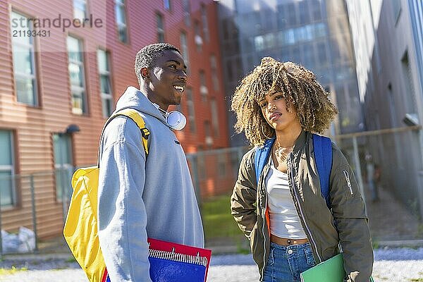 Cool multiethnic students outside the university holding notebooks and carrying rucksack