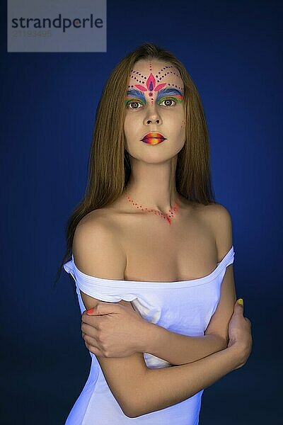 Young girl with bright UV make-up artistic portrait against blue background