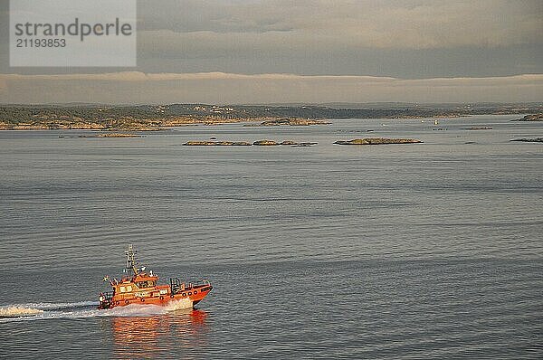 Red lifeboat on the sea in motion  islands and cloudy sky in the background  Gothenburg  Baltic Sea  Sweden  Europe