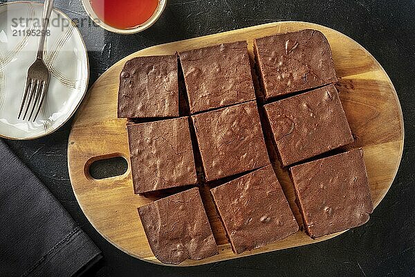 Schokoladen Brownie  einfacher Kaffeekuchen  Draufsicht auf einen schwarzen Hintergrund  in quadratische Stücke geschnitten  Food Fotografie