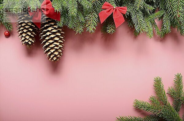 Flat lay design of Christmas greeting card of fir twigs bows and cones on pink background. Space for text