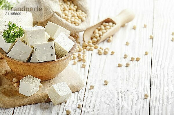 Soy Bean curd tofu in wooden bowl and in hemp sack on white wooden kitchen table. Non-dairy alternative substitute for cheese. Place for text