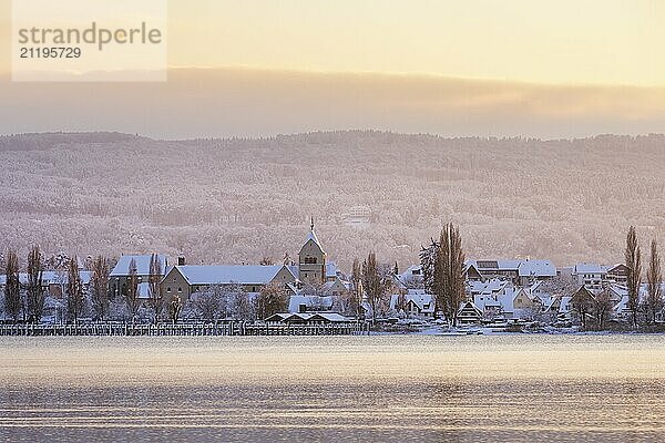 A snow-covered village at dusk  surrounded by a hilly winter landscape View of the Minster of St Mary and St Mark on the island of Reichenau  Seegarten  Allensbach  Lake Constance  Baden-Württemberg  Germany  Europe