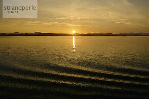 Sunrise over the sea with silhouetted mountains and an orange sky  Bergen  Vestland  Norway  Europe