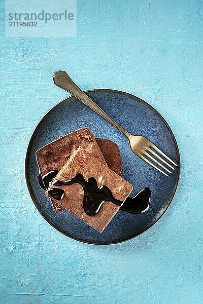 Schokoladen Brownie mit Sirup Tropfen  einfacher Kaffeekuchen  Overhead Flat Lay Aufnahme auf einem leuchtend blauen Hintergrund  Food Fotografie