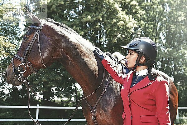 A young girl talking and takes care of her horse. She loves the animals and joyfully spends her time in their environment